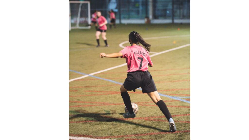 Long passing in soccer - A soccer female player kicking a long ball
