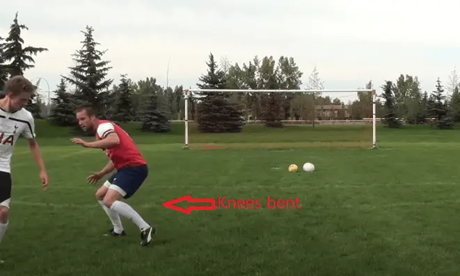How to defend in soccer - A striker facing a defender on a training pitch. The defender is bending to avoid being easily dribbled