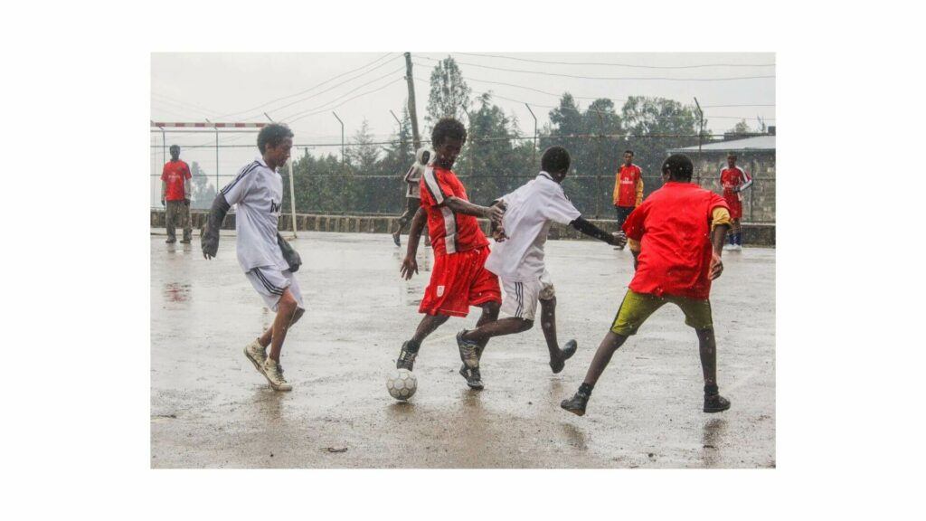 Can you playing soccer in the rain - A bunch of kids playing soccer in the rain