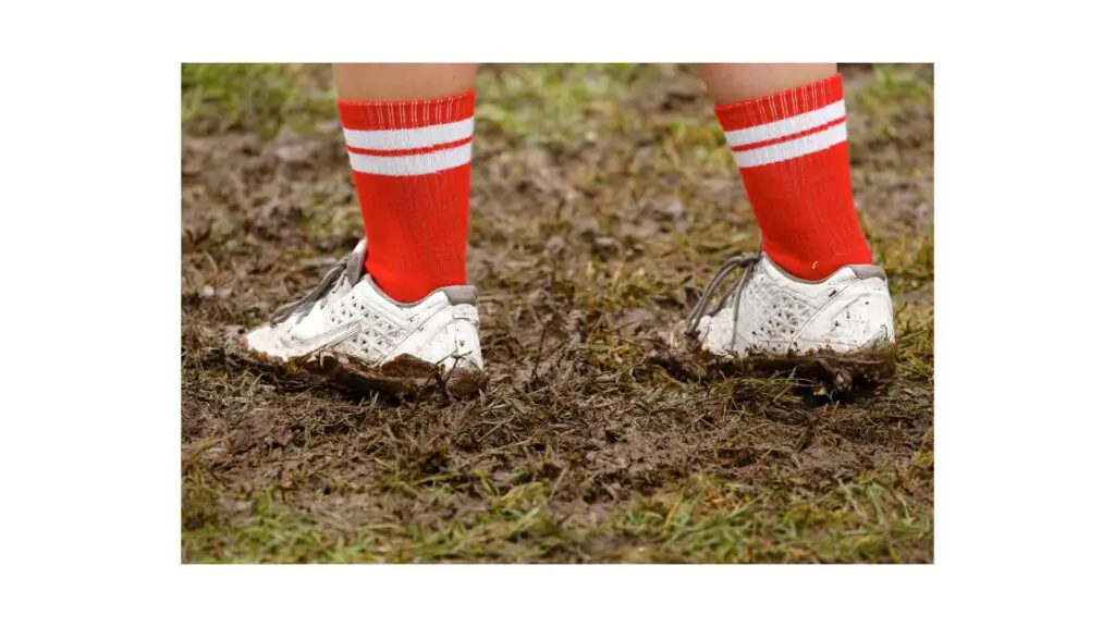 Baseball cleats vs Soccer cleats - someone standing in dirty grass covering his cleats