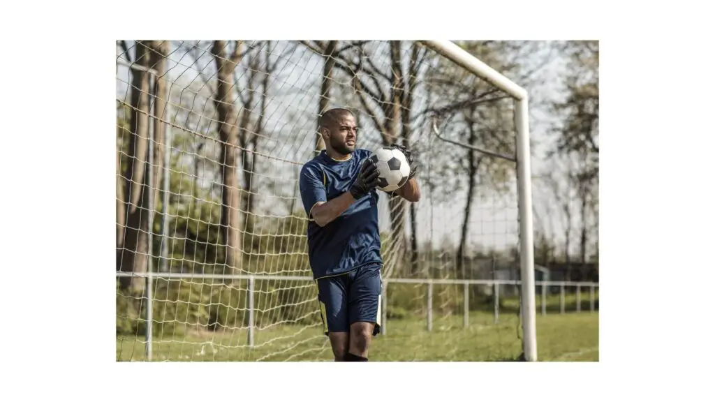 Understanding soccer positions - A goalie holding a ball in his goal