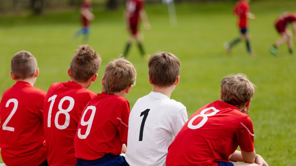 Motivation for soccer players - soccer kids sitting on the bench and watching the game