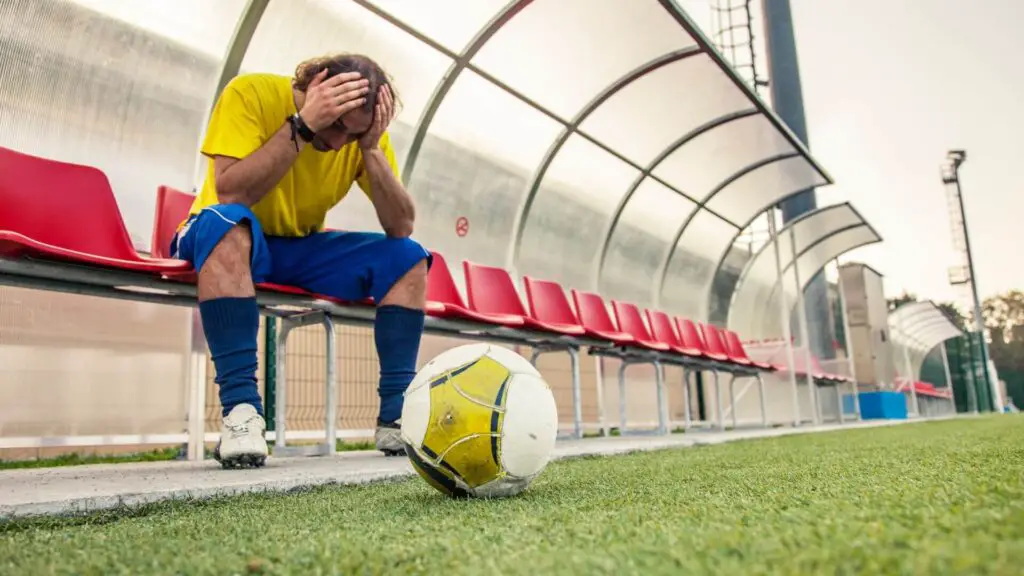 How do I get rid of anxiety in soccer - soccer player sadly sitting with both hands on his head