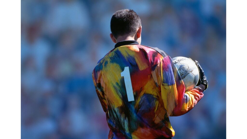 Why Do Goalkeepers Wear Number 1 - a soccer goalie wearing a coloured long sleeve shirt and holding a ball