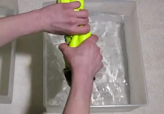 How to Dry Goalkeeper Gloves Fast - Someone squeezing yellow goalie gloves to dry them