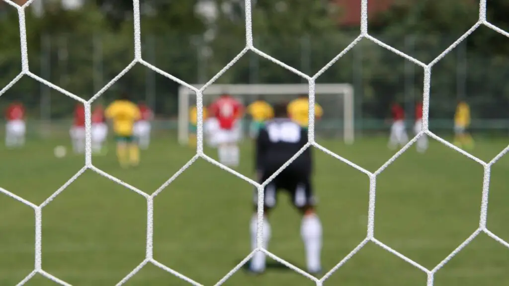 How Do Goalkeepers Keep Their Hands Warm - a blurry picture of a goalkeeper watching his teammates from his goal