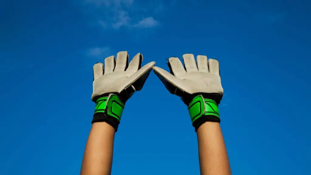 What are soccer goalie gloves made of - Two raised hands wearing goalie gloves