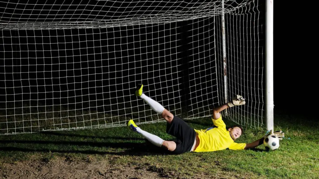 Are Reusch goalkeeper gloves good - A soccer goalie diving and making a save on the ground