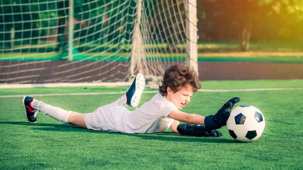 Why do goalkeepers wear gloves - Young soccer goalie catching the ball