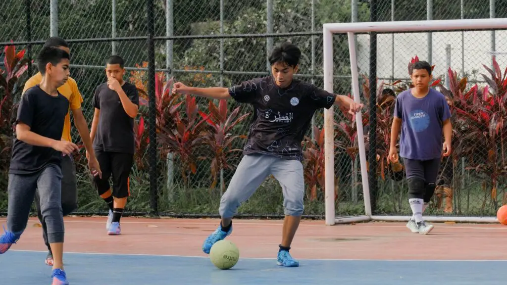 Can goalkeepers wear gloves in Futsal - Young soccer players playing on Futsal pitch and the goalie doesn't wear gloves