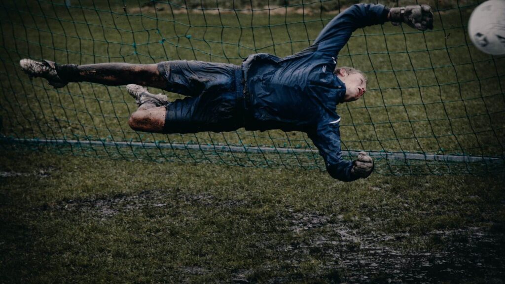 what do goalkeepers wear under T shirt - Soccer goalie diving to make a save