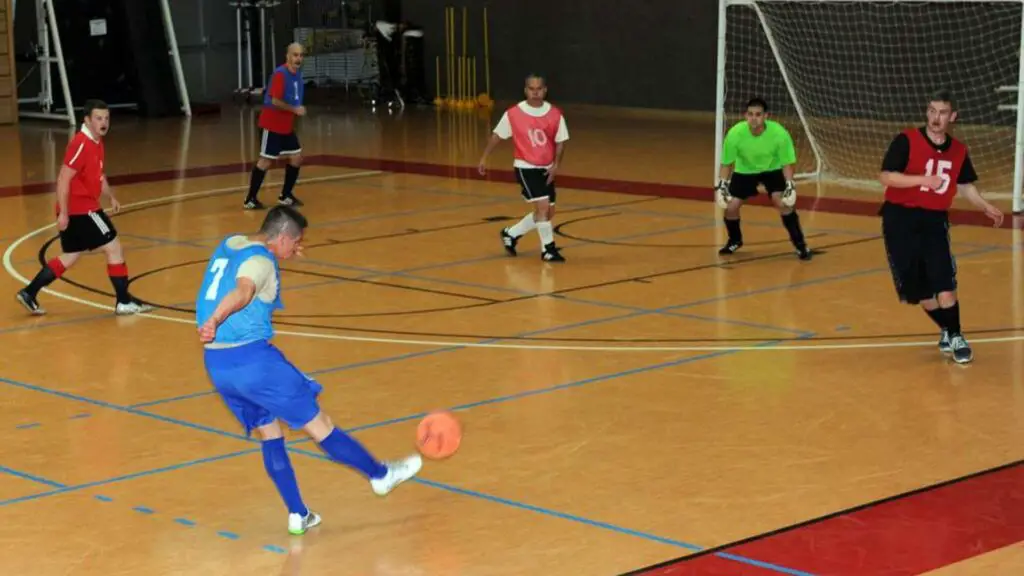 Difference between Futsal and Indoor soccer - Player shooting the ball on Futsal pitch