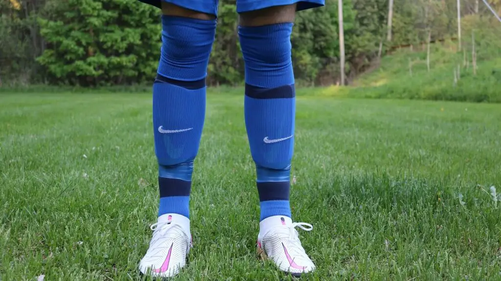 what are soccer shin guards made of - Two legs wearing blue socks with shin guards under